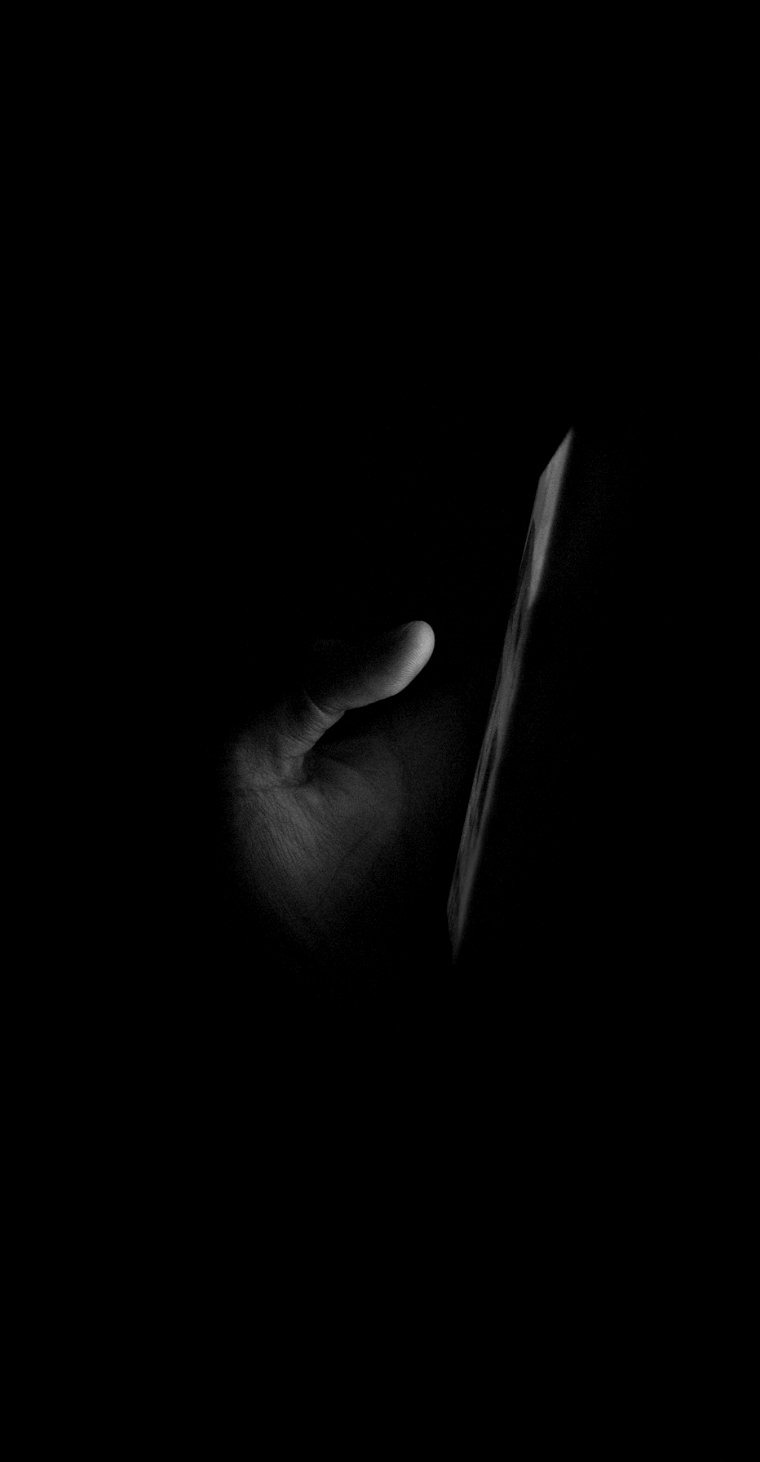 Hand holding a smartphone in a dark room